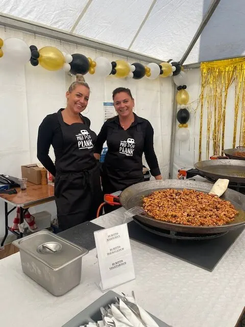 Chantal en collega achter de paellapan op een feest