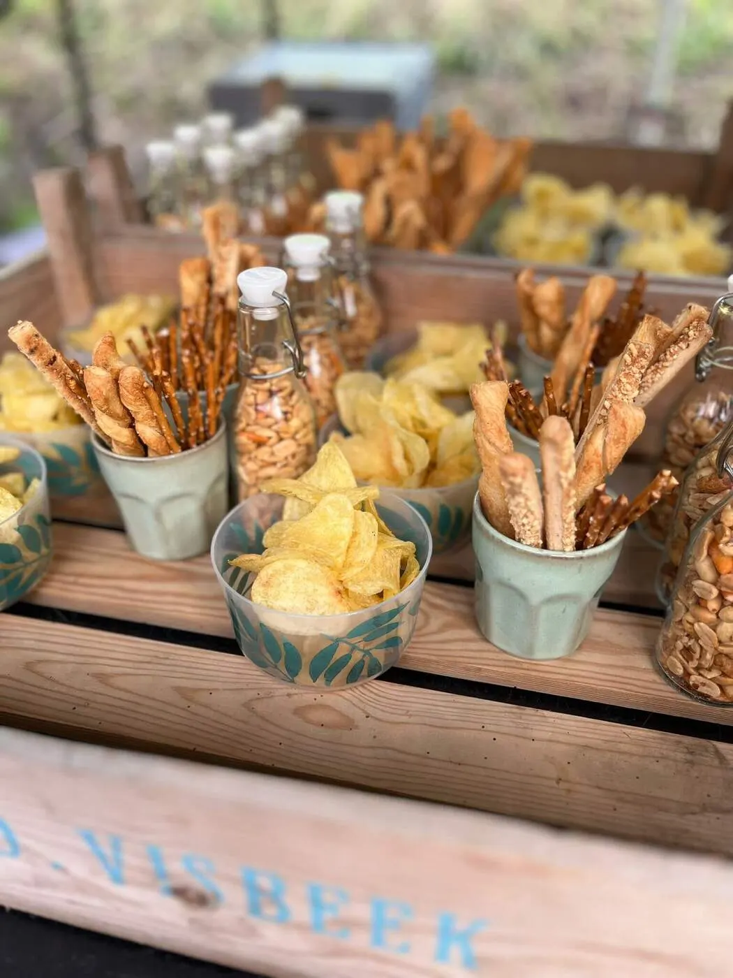 Krat met bakjes chips en soepstengels voor bij de borrel