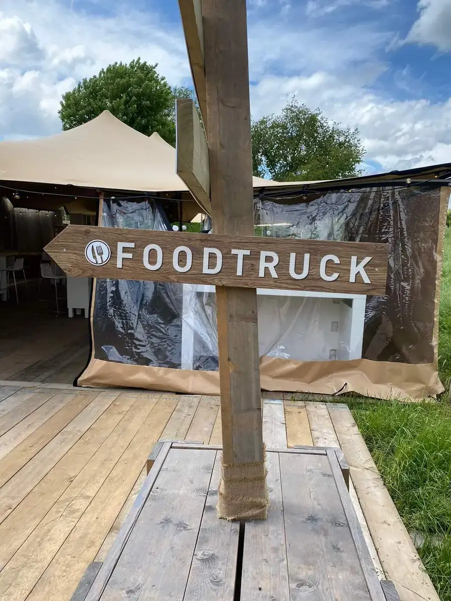 Houten foodtruck-wegwijzer op een festivalterrein